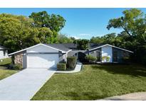 Charming single-story home with attached garage, well-manicured lawn, and lush landscaping at 7504 Lily Pad Ct, Hudson, FL 34667