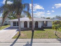 Charming single-story home with arched windows, palm trees, and a well-maintained front yard under a sunny sky at 7553 Sequoia Dr, New Port Richey, FL 34653