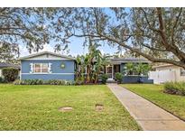 Charming blue home with well-manicured lawn, lush landscaping, and a welcoming walkway leading to the entrance at 818 37Th Ne Ave, St Petersburg, FL 33704