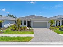 Charming single-story home featuring a well-manicured lawn and a brick driveway leading to a two-car garage at 17920 Nadine Pl, Nokomis, FL 34275