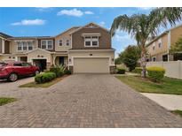 Charming two-story townhome featuring a brick paved driveway, attached garage, and well-manicured landscaping at 2117 Lake Waters Pl, Lutz, FL 33558