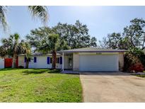 Charming single-story home featuring a well-manicured lawn and a two-car garage at 2131 Cedar Dr, Dunedin, FL 34698