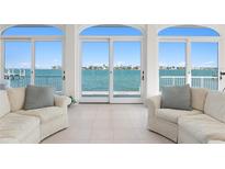 Bright living room with white tile floor and large glass doors revealing beautiful water view at 2171 E Vina Del Mar Blvd, St Pete Beach, FL 33706