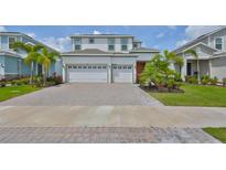 Beautiful two-story home with a brick driveway, three-car garage, and lush landscaping at 933 Signet Dr, Apollo Beach, FL 33572