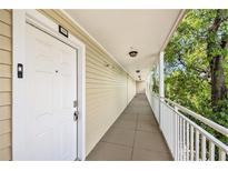 Condo hallway with door number 207 and railing with view of trees at 1000 W Horatio St # 207, Tampa, FL 33606