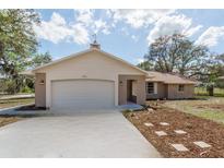 Charming one-story home with a two-car garage, light brick accents, and a well-manicured front yard at 11480 Genter Dr, Spring Hill, FL 34609