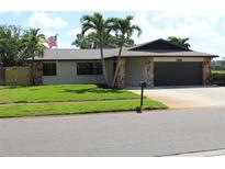 Charming single-story home with stone accents, lush lawn, and mature palm trees at 12619 98Th St, Largo, FL 33773