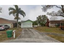 Well-maintained single Gathering home featuring a two car garage, a landscaped yard, and a long concrete driveway at 8851 Magnolia Pl, Seminole, FL 33777