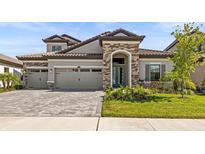Charming two-story home featuring a stone facade, well-manicured lawn, and a three-car garage at 11014 Rustic Timber Loop, San Antonio, FL 33576