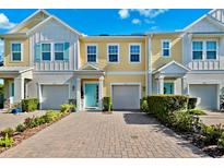 Charming multi-story townhomes featuring colorful exteriors, attached garages, and a welcoming paver driveway at 1103 Coral Ln, Dunedin, FL 34698