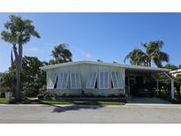 Charming single-story home featuring decorative window shutters and a covered carport, surrounded by lush tropical landscaping at 121 Dolphin S Dr, Oldsmar, FL 34677