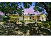 Charming single-story home with mature landscaping, stone accents, and a red front door at 1320 Whispering Pines Dr, Clearwater, FL 33764