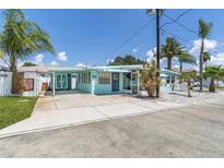 Charming light blue home featuring a carport and a small, inviting front porch with white trim at 13200 Boca Ciega Ave, Madeira Beach, FL 33708