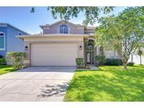 Charming two-story home featuring a well-manicured lawn, a two-car garage, and mature landscaping at 1632 Gray Bark Dr, Oldsmar, FL 34677