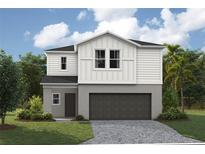 Charming two-story home with a gray stucco and white plank exterior and well-maintained landscaping at 37213 Sagemoor Dr, Zephyrhills, FL 33541