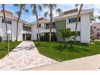 Charming condo building showcasing lush tropical landscaping and a welcoming brick walkway at 311 Island Way # 101, Clearwater Beach, FL 33767