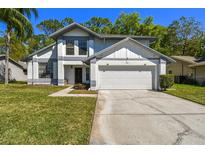 Charming two-story home featuring a two-car garage, well-manicured lawn, and classic architectural details at 389 Waterford W Cir, Tarpon Springs, FL 34688