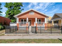 Charming bungalow with a black metal fence, orange stucco, and a covered front porch at 6414 N Central Ave, Tampa, FL 33604