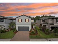 Charming two-story home with a well-manicured lawn, landscaped garden beds and a beautiful sunset at 10815 Windswept Garden Way, Tampa, FL 33647