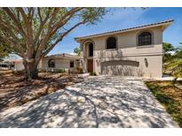 Stunning two-story home with a paver driveway and lush landscaping with a large tree in the front yard at 2063 Illinois Ne Ave, St Petersburg, FL 33703