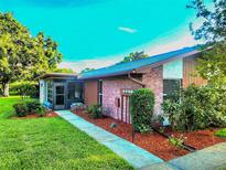 Charming single-story home featuring brick accents, a screened-in porch, and a well-maintained front yard with lush landscaping at 2241 Shelly Dr # D, Palm Harbor, FL 34684