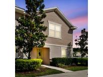 Charming townhome featuring neutral siding, manicured lawn, and welcoming entrance, bathed in a pleasant evening light at 5022 Chipotle Ln, Wesley Chapel, FL 33544