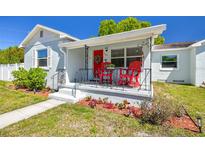 Charming home showcasing a delightful front porch with decorative railings, a red door, and vibrant landscaping at 503 N Macdill Ave, Tampa, FL 33609