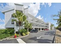 Coastal condo building featuring multi-story balconies, palm trees, and ample parking in a sunny setting at 515 Leffingwell Ave # 211, Ellenton, FL 34222