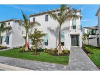 Modern, two-story home featuring a clean white exterior, palm trees, and manicured landscaping at 6023 Cat Claw Ln, Bradenton, FL 34210
