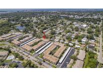 Expansive aerial view showcasing the condo complex with mature trees, a pond, and its prime location near the water at 10035 63Rd N Ave # 23, St Petersburg, FL 33708