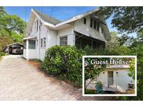 Charming two-story home with white siding, a carport, and a quaint guest house surrounded by lush greenery at 1107 S Prospect Ave, Clearwater, FL 33756
