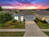 Charming single-story home with a well-manicured lawn and a two car garage at sunset at 13749 Hunting Creek Pl, Spring Hill, FL 34609