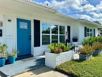 Inviting front porch with a blue door, beautiful plants and a cozy seating area at 14019 89Th Ave, Seminole, FL 33776