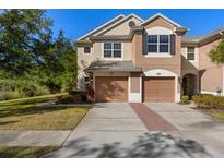 Two-story townhome boasts attached garages, neutral stucco, and meticulously maintained landscaping at 26517 Castleview Way, Wesley Chapel, FL 33544