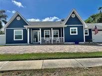 Charming blue home with a quaint front porch and brick paved driveway at 3000 Tangerine Ter, Palm Harbor, FL 34684