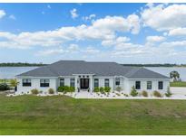Stunning lakefront home with lush green lawn, elegant landscaping, and a classic white facade under a sunny sky at 3409 Gulf City Rd, Ruskin, FL 33570