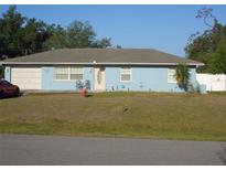 Charming light blue single story home with a well-manicured lawn and attached garage on a sunny day at 4179 Juniper St, Port Charlotte, FL 33948