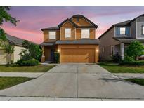 Two-story house with a driveway and attached two-car garage, surrounded by neatly manicured landscaping at 5147 Brickwood Rise Dr, Wimauma, FL 33598