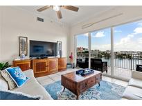 Bright living room featuring tile floors, comfortable seating, and a large window showcasing beautiful water views at 600 Bayway Blvd # 504, Clearwater Beach, FL 33767