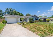 Charming single-story home with a well-manicured lawn, white painted brick, attached garage, and concrete driveway at 8421 Millwood Dr, Tampa, FL 33615