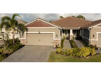 Charming home featuring a brick-paved driveway, two-car garage, manicured landscaping, and a welcoming entrance at 8732 Rain Song Rd, Sarasota, FL 34238