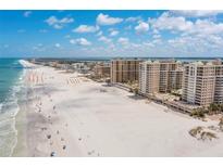 Stunning aerial view of beachfront condos and the shoreline with white sand and clear blue skies at 11 San Marco St # 407, Clearwater Beach, FL 33767
