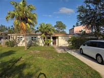 Charming single-story home with palm trees, a well-manicured lawn, and a private driveway at 3919 Harrisburg Ne St, St Petersburg, FL 33703
