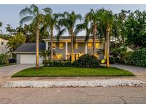Elegant two-story home featuring mature palm trees, lush landscaping, and a spacious front yard at 4106 W Cleveland St, Tampa, FL 33609