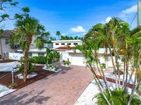 Charming home featuring a brick driveway, two-car garage, and beautifully landscaped yard with lush tropical plants at 5430 Avenida Del Mare, Sarasota, FL 34242