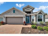 Charming home with a brick walkway, gray stone accents, teal door, well-maintained landscaping, and a two-car garage at 11773 Little River Way, Parrish, FL 34219