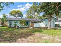 Charming single-story home with a well-manicured lawn, mature trees, and a light blue exterior paint at 14199 82Nd Avenue, Seminole, FL 33776
