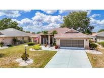 Charming single-story home with well-maintained landscaping, screened garage, and cozy front porch at 2018 E Del Webb Blvd, Sun City Center, FL 33573