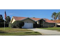 Charming single-story home with a red tile roof, well-maintained landscaping, and an attached two-car garage at 2704 E Montague E Ct, Clearwater, FL 33761