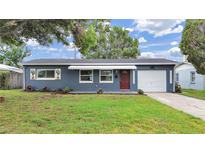 Charming one-story home with blue exterior, awning, red door, manicured lawn and single car garage at 5772 4Th N Ave, St Petersburg, FL 33710